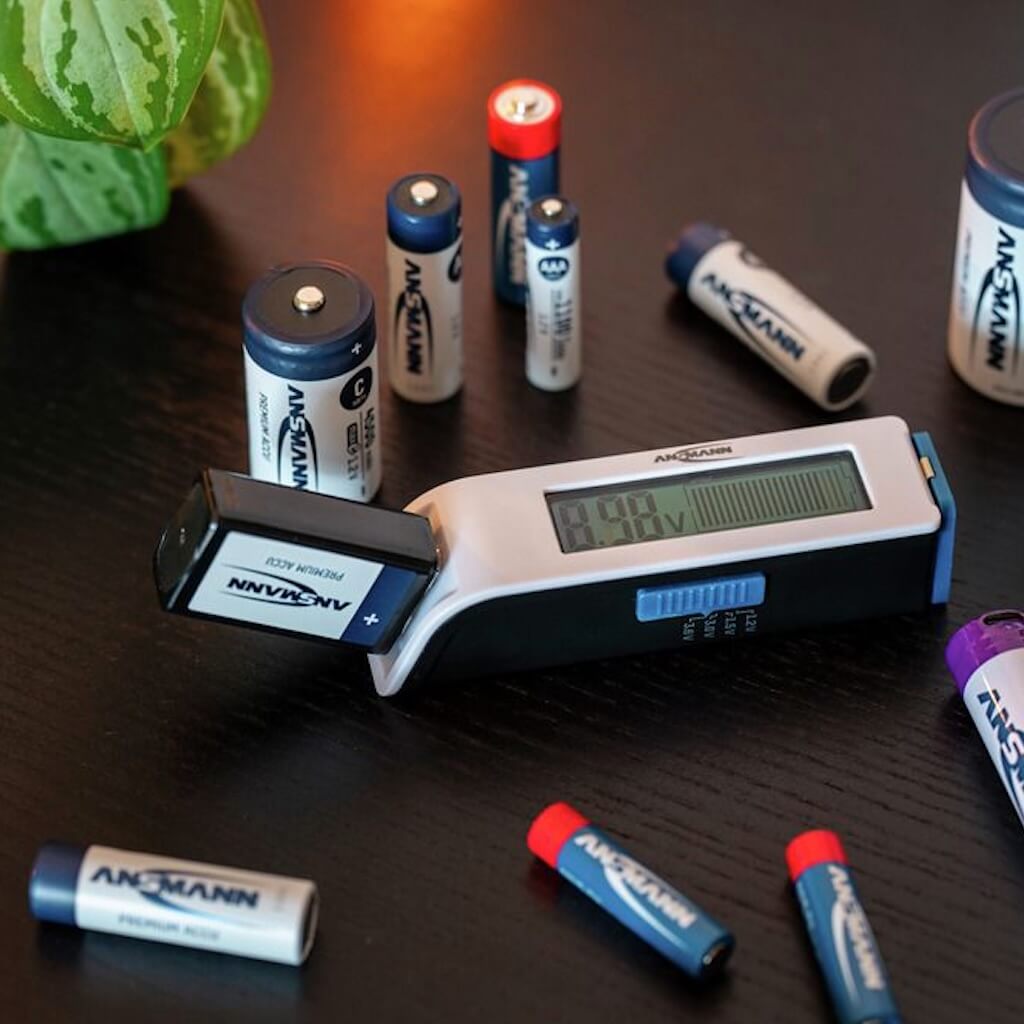 Ansmann Comfort Check - Pocket-Size Universal Battery Tester, shown with assorted batteries