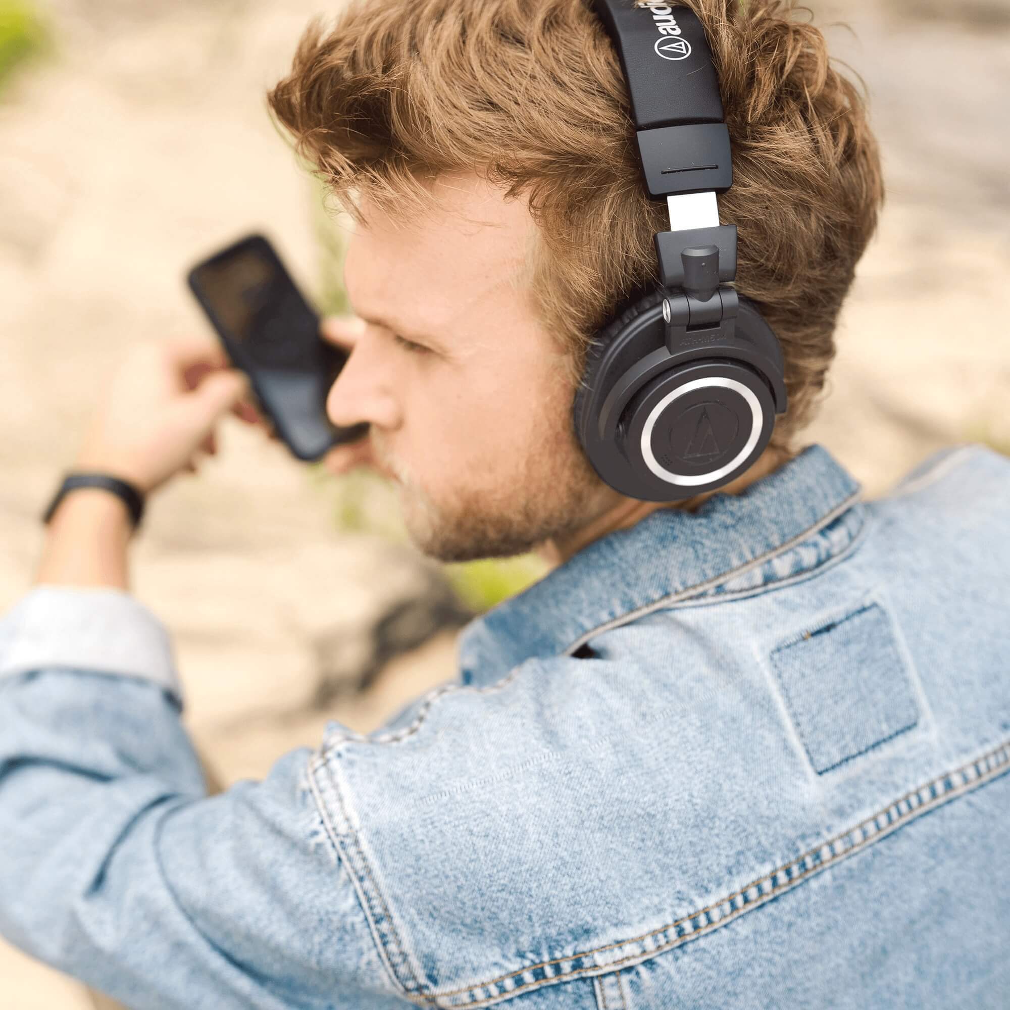 Audio-Technica ATH-M50xBT2 Bluetooth Wireless Over-Ear Headphones on a young man listening to music on his phone