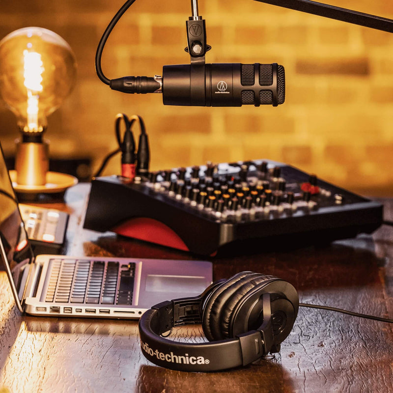 Audio-Technica AT2040 - Hypercardioid Dynamic Podcast Microphone, mounted on a boom in a home studio, shown with a mixer, laptop, and headphones