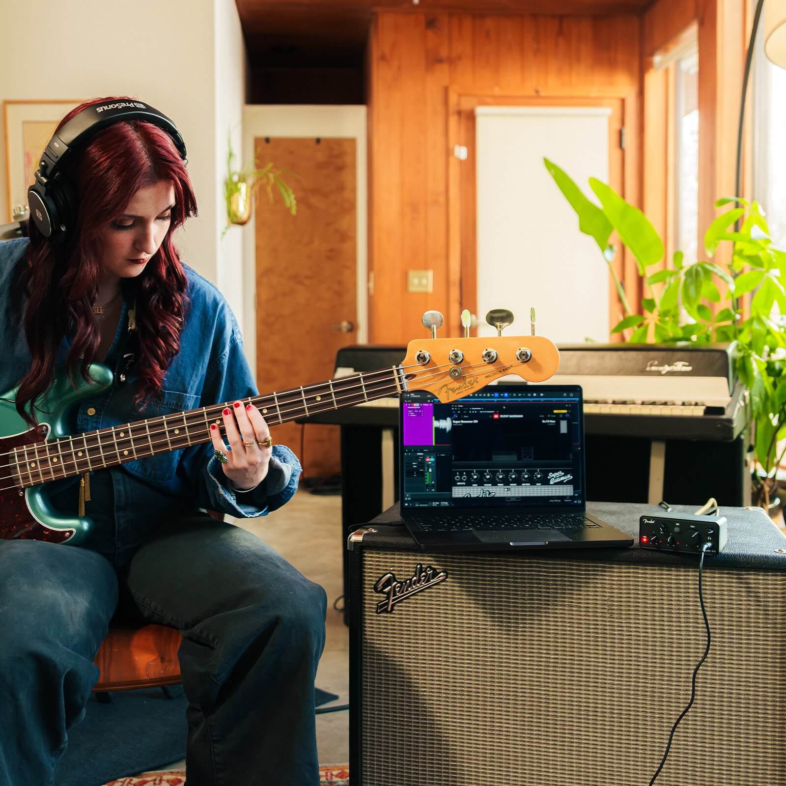 Person playing bass guitar with a Fender AudioBox Go USB-C audio interface in a home setting
